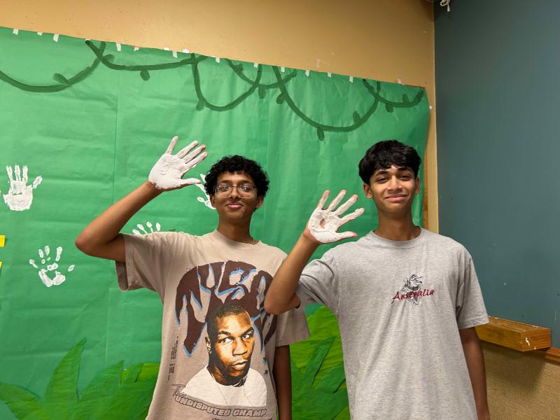 Two TAMS Students waving in front of art project