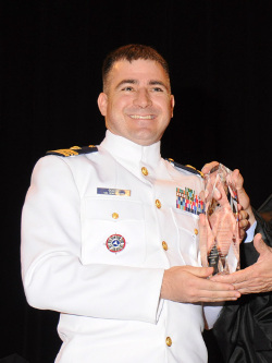 Lieutenant Commander Peter Gooding in white uniform holding award